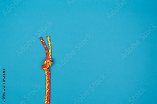 Overhand knot with red and yellow climbing rope on blue background © Eduardo