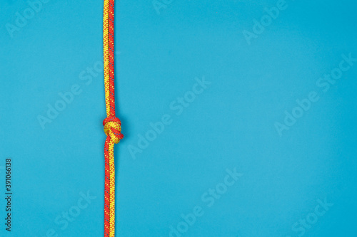 Overhand knot with red and yellow climbing rope on blue background photo