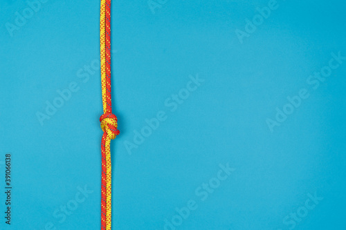Photography Overhand knot with red and yellow climbing rope on blue background
