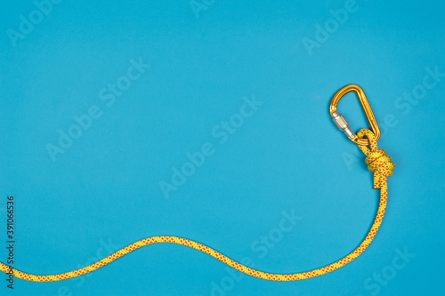 Overhand knot with yellow carabiner and climbing rope on blue background