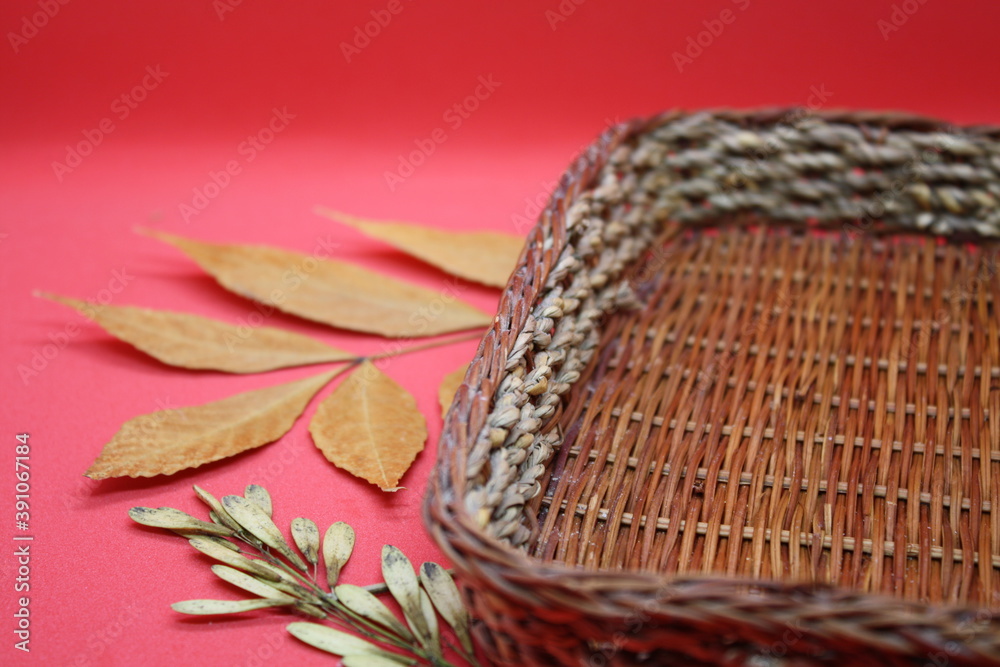 autumn leaves and a wicker basket on a red background.