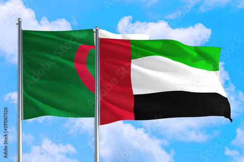 United Arab Emirates and Algeria national flag waving in the windy deep blue sky. Diplomacy and international relations concept.