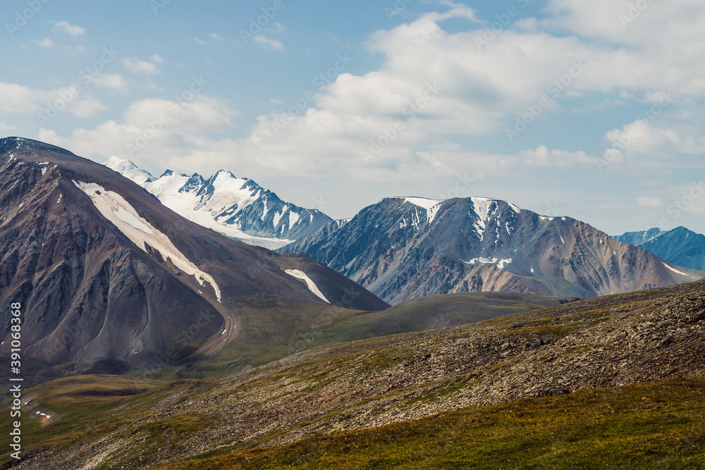Scenic landscape with great mountain range and glacier. Snow on top of giant mountain ridge. Beautiful big snowy mountains in sunny day. View from pass to snowy peak and glacial mounts in sunlight.