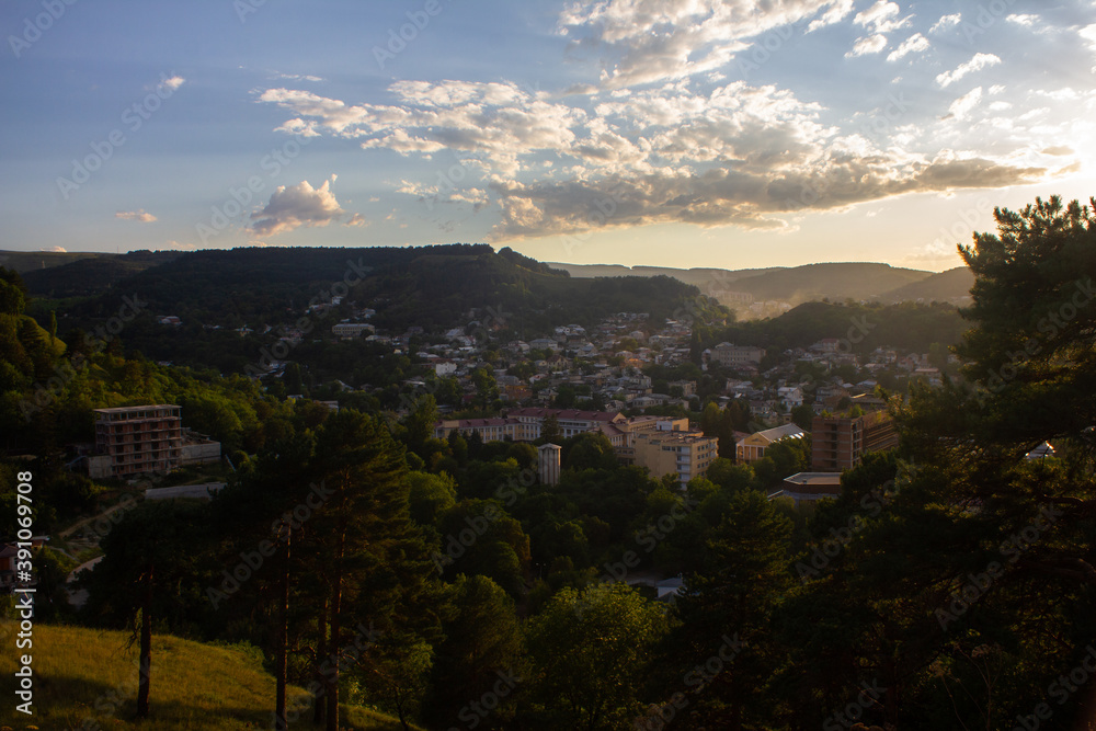 View from the mountain to the city park and houses with sunbeams