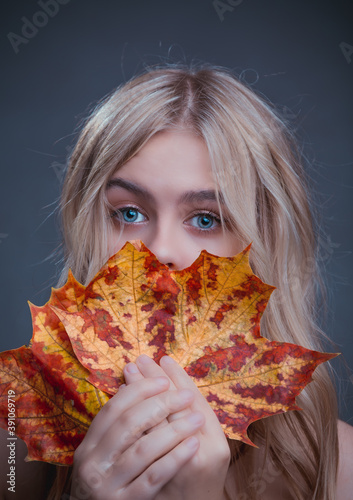Portrait of a girl with a yellow maple leaf