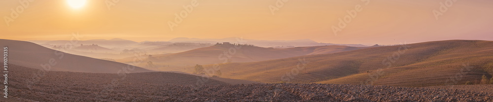 Morning pink colored panorama of Tuscany landscape with mist over rolling hills