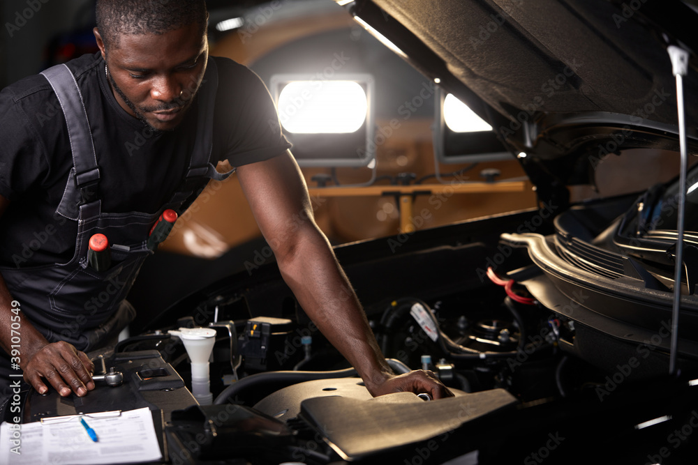 Foto Stock professional car mechanic is examining engine under the hood at auto  repair shop, make notes, checking notes in notebook | Adobe Stock