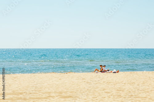 Gribovka, Ukraine - July 2, 2020: couple sitting on the beach reading book. sunbathing