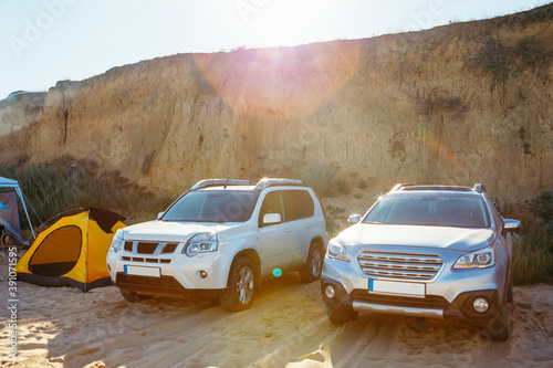 two cars parked at sandy beach near tent