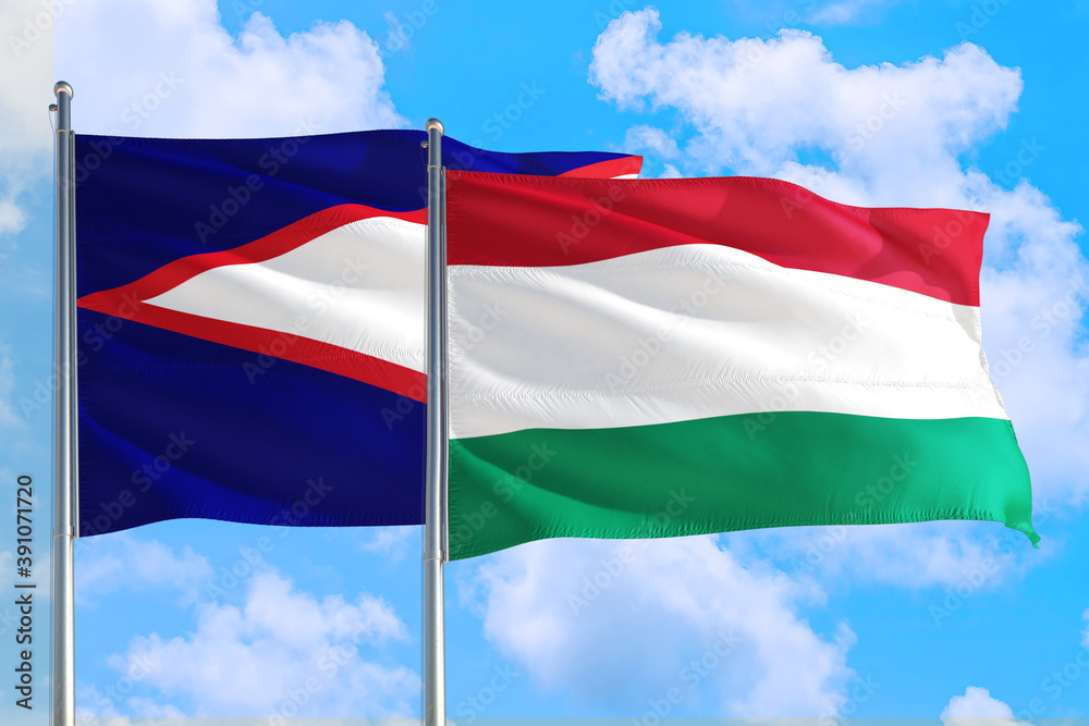 Hungary and American Samoa national flag waving in the windy deep blue sky. Diplomacy and international relations concept. Hungary and American Samoa national flag waving in the windy deep blue sky. Diplomacy and international relations concept.
