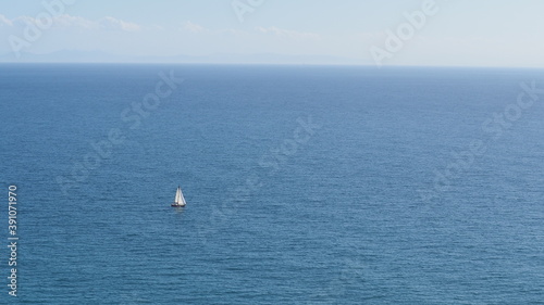 Sailboat sailing alone and in the distance in the middle of the sea on a sunny day