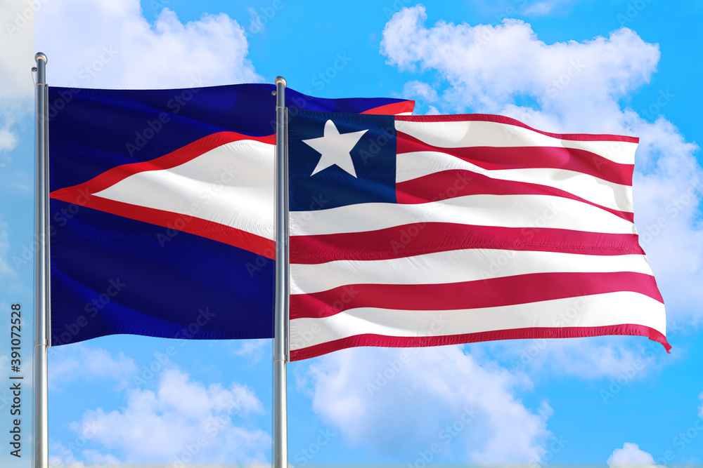 Liberia and American Samoa national flag waving in the windy deep blue sky. Diplomacy and international relations concept. Liberia and American Samoa national flag waving in the windy deep blue sky. Diplomacy and international relations concept.