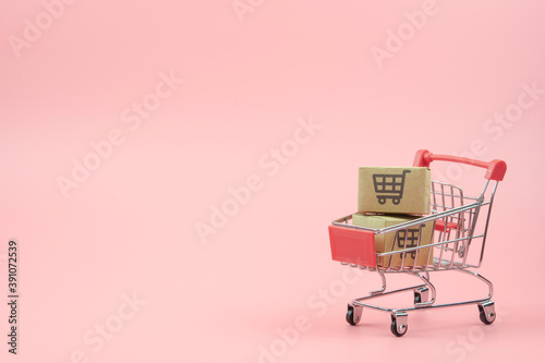 Shopping concept - Cartons or Paper boxes in red shopping cart on pink background. online shopping consumers can shop from home and delivery service. with copy space.