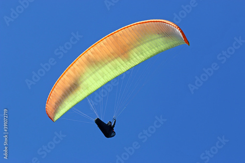 Paraglider flying yellow wing in a blue sky 