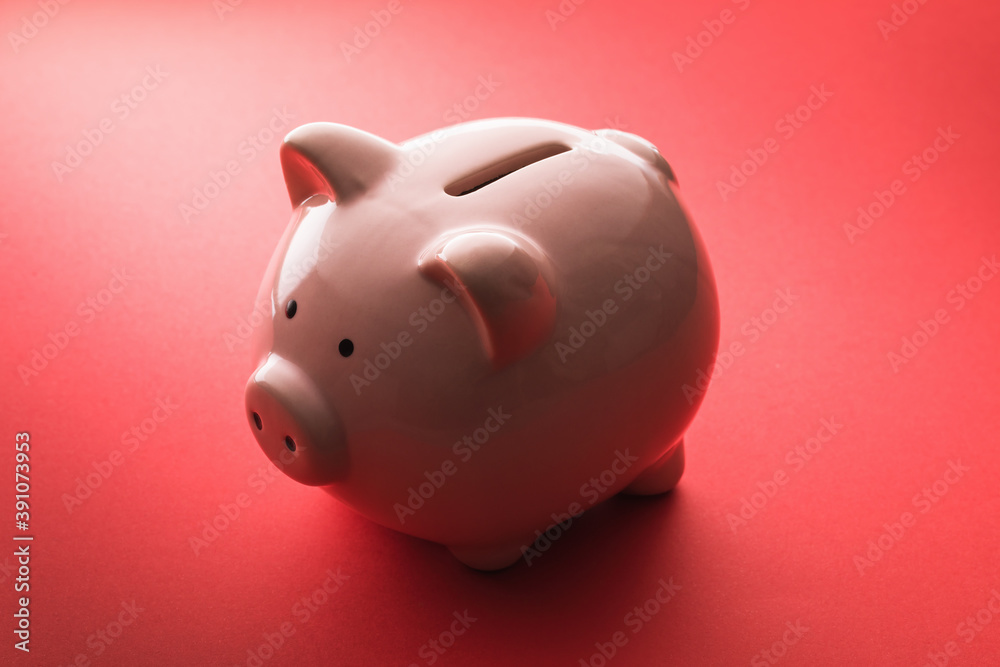 Pink ceramic piggy bank on red background, close-up