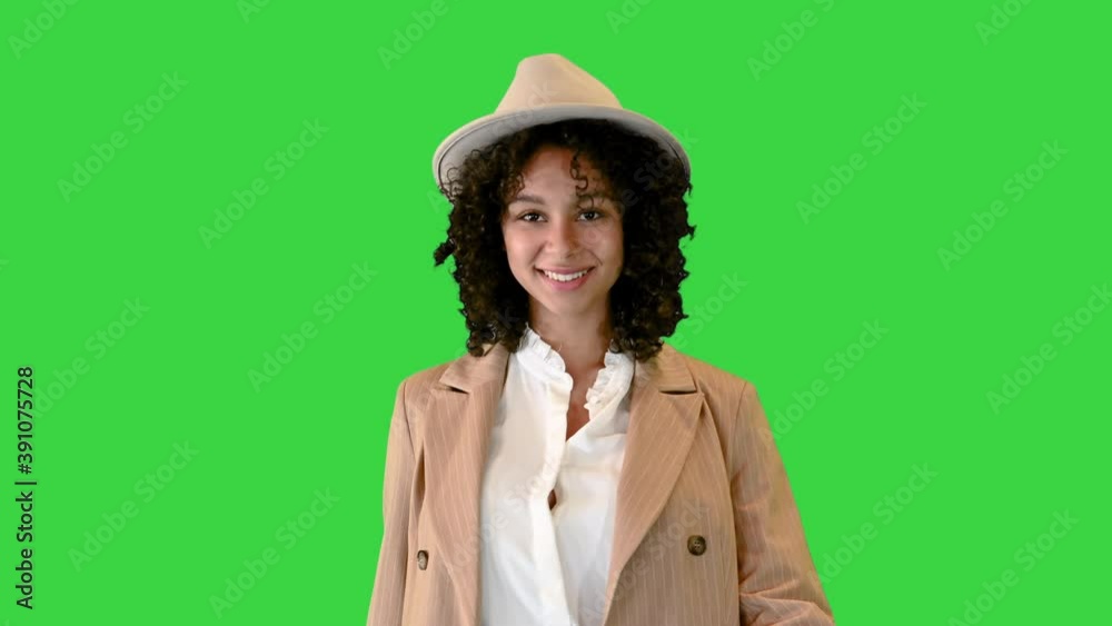 Young african american woman in a hat stumbled while walking and smiling on a Green Screen, Chroma Key. Young african american woman in a hat stumbled while walking and smiling on a Green Screen, Chroma Key.