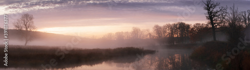 Banner panoramic autumn landscape fog over river and sky with rising sun