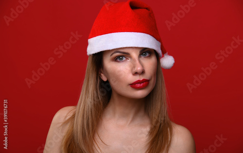 Portrait of a young woman in Santa's hat against a red background. The concept for the new year and Christmas.