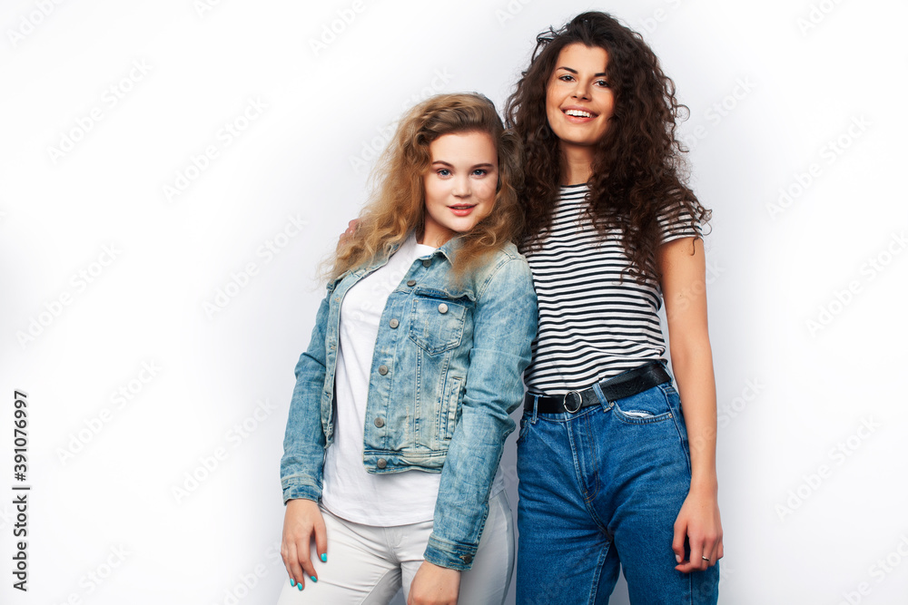 young pretty teenage girls friends with blond and brunette curly hairs posing cheerful isolated on white background, lifestyle people concept young pretty teenage girls friends with blond and brunette curly hairs posing cheerful isolated on white background, lifestyle people concept