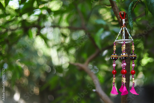 Pink windchime decoration hanging from a tree brunch and beautiful green leaves in nature- with space to write your text 