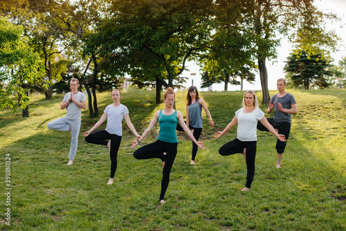 A group of people do yoga in the Park at sunset. Healthy lifestyle, meditation and Wellness © Andrii