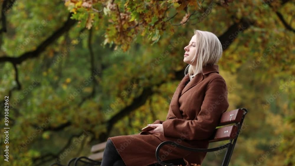Woman sitting on a bench in a autumn park