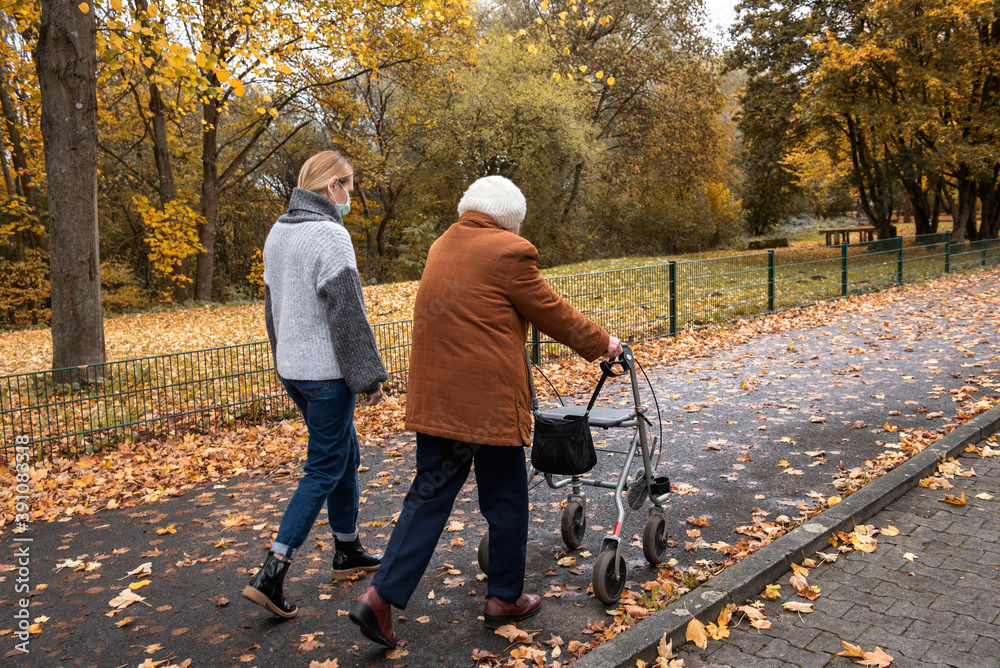 Fototapeta premium Elderly woman taking a walk with granddaughter with the help of a walker in winter