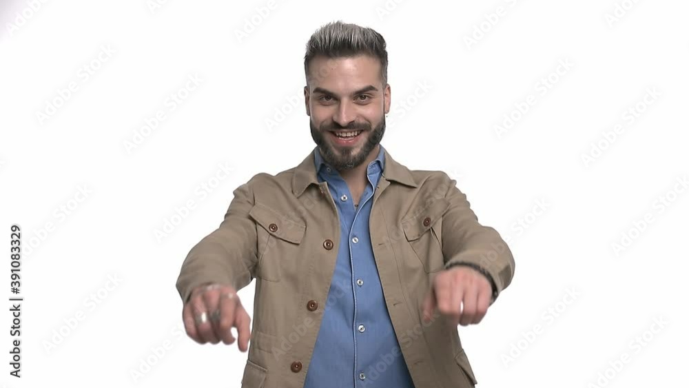 enthusiastic casual guy in denim shirt looking down, pointing fingers and laughing, standing isolated on white background in studio enthusiastic casual guy in denim shirt looking down, pointing fingers and laughing, standing isolated on white background in studio