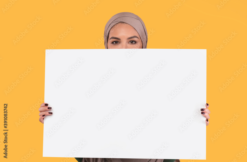 Islamic Woman In Hijab Holding Empty Poster On Yellow Background Islamic Woman In Hijab Holding Empty Poster On Yellow Background