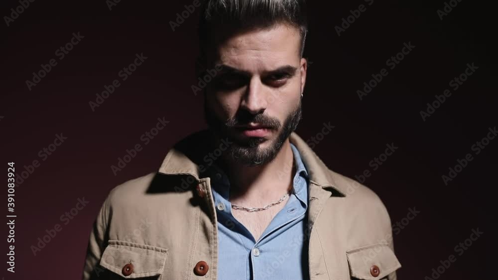 mysterious young casual man in denim shirt looking down, sensually putting glasses and posing in a fashion light on pink background in studio