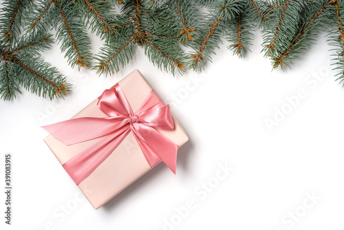 A row of fir branches and a gift box with a bow isolated on a white background.