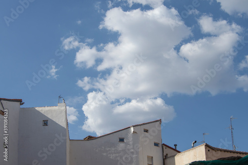 several white facade buildings and rooftops with a sky with white clouds above