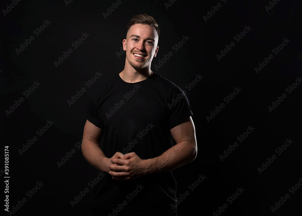 Handsome and fit bodybuilder posing on black background in workout gear