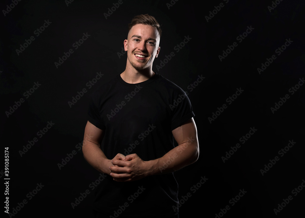 Handsome and fit bodybuilder posing on black background in workout gear Handsome and fit bodybuilder posing on black background in workout gear