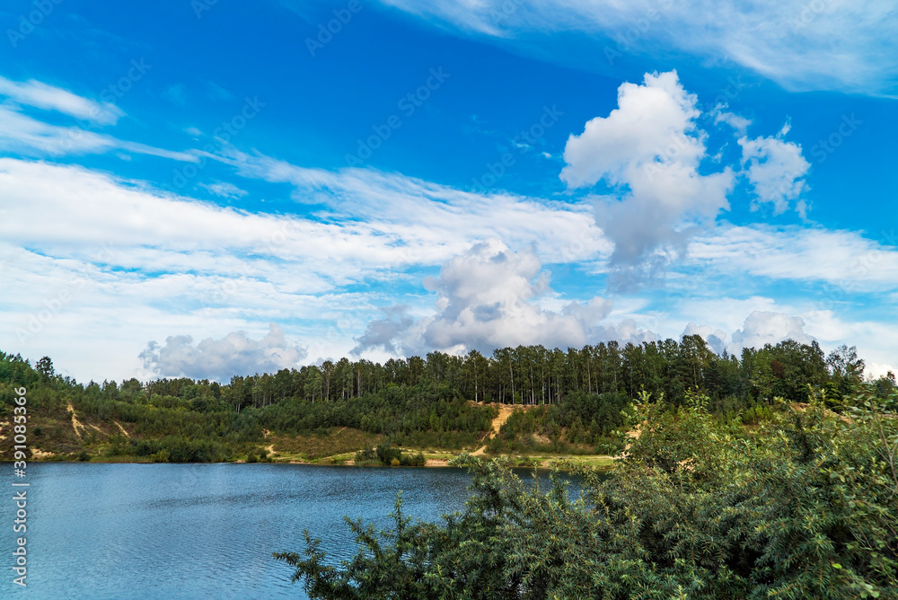 Obraz premium White clouds in the blue sky over the lake in summer.