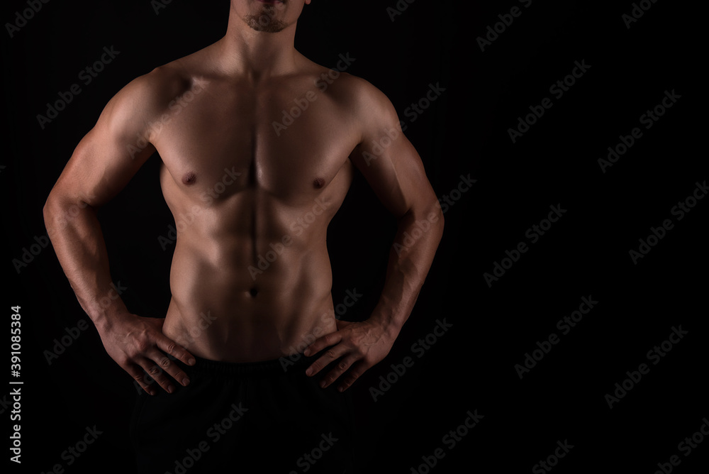 Fototapeta premium Muscular male torso of fit bodybuilder on black background