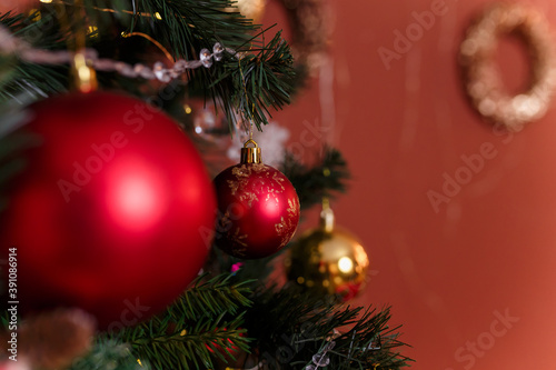 Close up of fir-tree branches decorated with red and golden baubles and garlands. Winter holidays, magic, Merry Christmas, Happy New Year concept, copy space.
