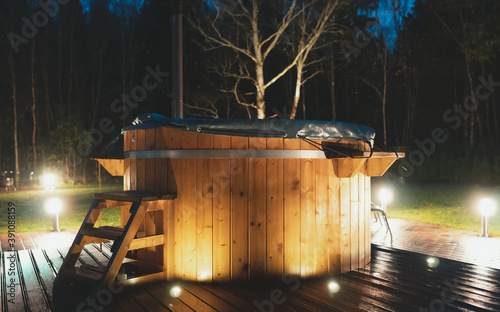 Obraz na płótnie Wooden hot tub with fireplace at night.
