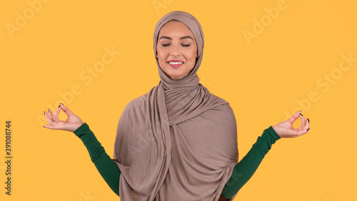 Muslim Woman In Hijab Meditating With Eyes Closed, Yellow Background