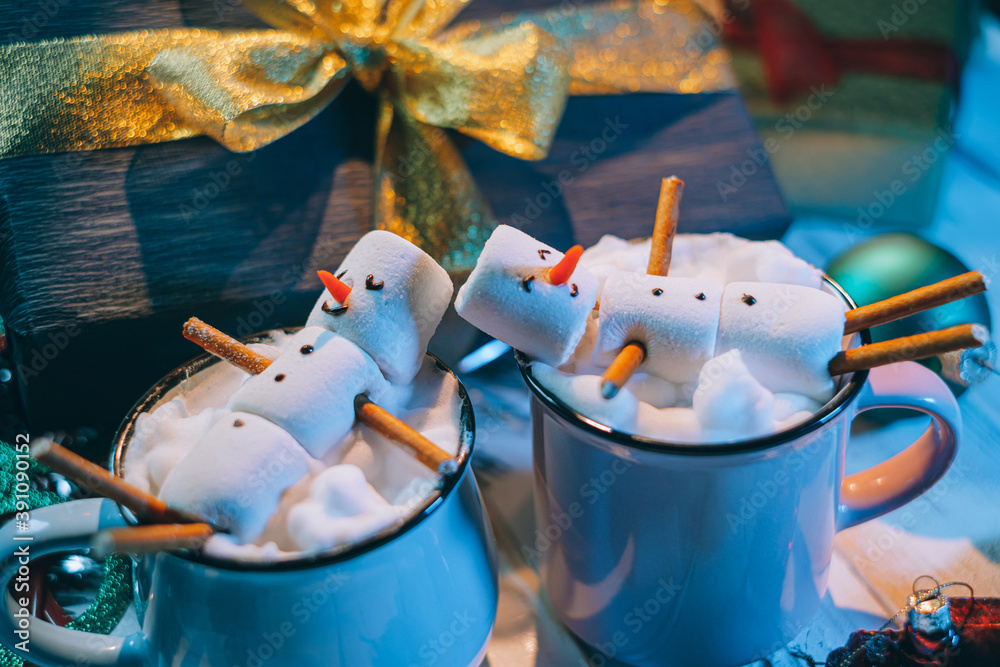 a mug with hot chocolate on a wooden table with a marshmallow man who is resting in a mug