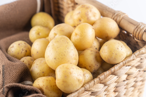 New raw potatoes in a wicker basket on a brown background close up