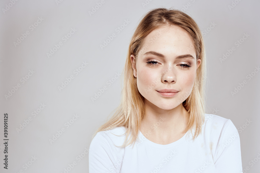 Cheerful blonde woman in white t-shirt cropped view light background