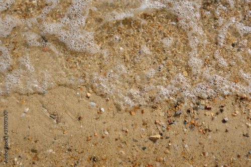 White foam bubbles on the seashore on a bright sunny day. Sea wave. Rest at the sea.
