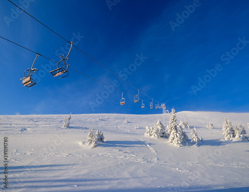 Alpine resortr ski lift with seats going over the sunrise mountain skiing freeride slopes and fir tree groves
