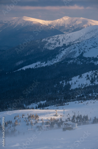 Alpine resortr ski lift with seats going over the sunset mountain skiing  slopes in extremally windy weather photo