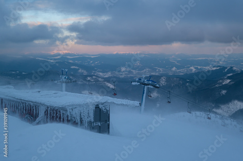 Alpine resortr ski lift with seats going over the sunset mountain skiing  slopes in extremally windy weather photo