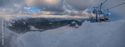 Alpine resortr ski lift with seats going over the sunset mountain skiing  slopes in extremally windy weather photo