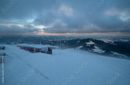 Alpine resortr ski lift with seats going over the sunset mountain skiing  slopes in extremally windy weather photo