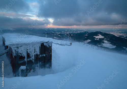 Alpine resortr ski lift with seats going over the sunset mountain skiing  slopes in extremally windy weather photo