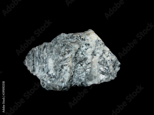 Sample of raw white with black inclusions of magnesite on a black background